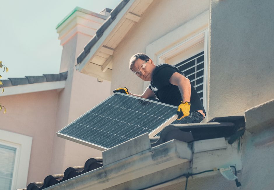 Artisan installant des panneaux solaires sur le toit d'une maison